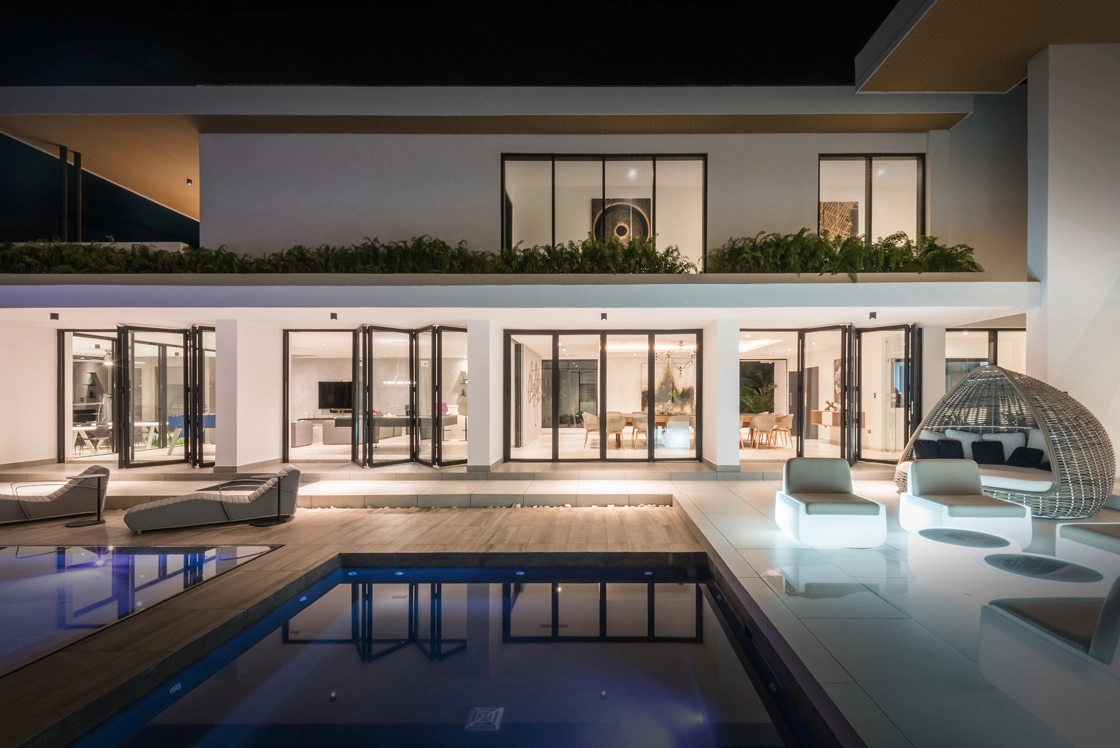 Luxury modern home with bifold doors and pool at night